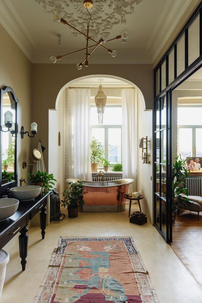 A serene bathroom showcasing vintage and modern design with a copper bathtub and lush plants.